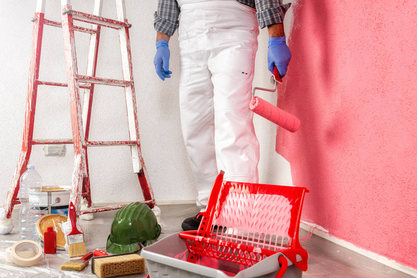 Beyaz Tulum, renkli boyama duvar boyama silindiri ile beyaz ev ressam işçi. İnşaat Sanayi. - Fotoğraf, Görsel