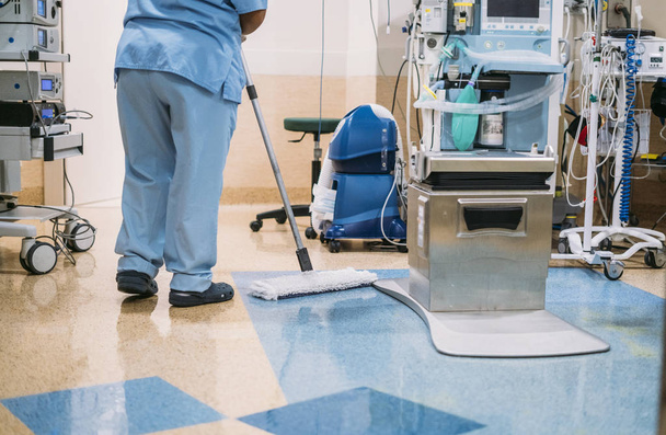 Концептуальне фото працівника лікарні, який робить прибирання в операційній кімнаті
 - Фото, зображення