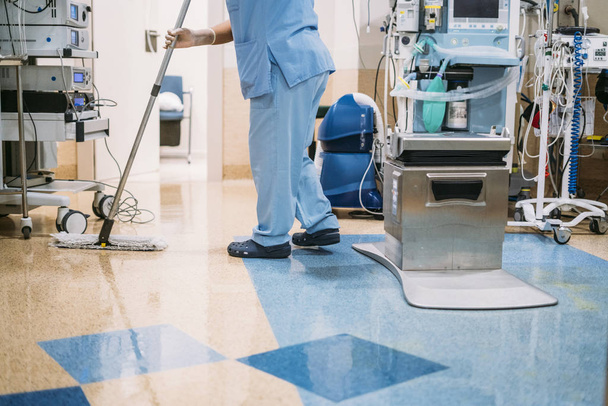 Concepto foto de un trabajador del hospital haciendo limpieza en la sala de operaciones - Foto, Imagen
