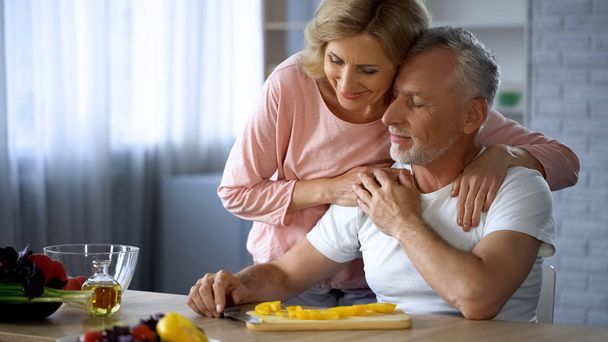 Happy retired couple hugging at home kitchen, love and harmony, cooking leisure - Fotoğraf, Görsel