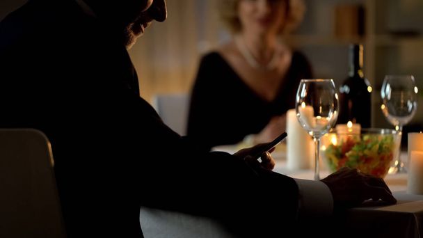 Businessman ignoring wife on romantic date, reading news on gadget, addiction - Foto, immagini