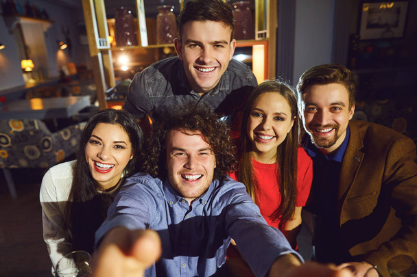 Friends make selfie on the phone in a restaurant. - Фото, изображение