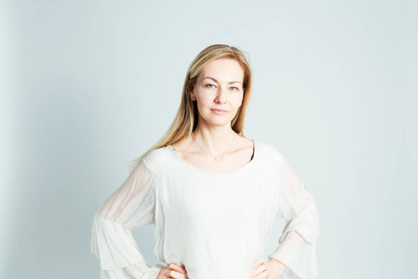 Porträt einer schönen Frau in einem weißen Kleid vor weißem Hintergrund - Foto, Bild