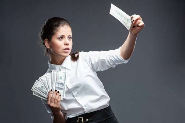 Молодая женщина с деньгами. Проверяет банкноту
 - Фото, изображение