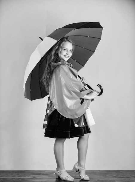 Waterproof accessories manufacture. Kid girl happy hold colorful umbrella wear waterproof cloak. Waterproof accessories make rainy day cheerful and pleasant. Confident in her fall garments - Fotó, kép