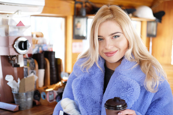 очаровательная милая блондинка в синем пальто с кофе в руке, тема людей и напитков
 - Фото, изображение