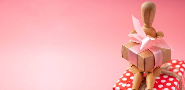 Puinen lelumalli, jolla on lahjoja vaaleanpunaisella taustalla. Konsepti loma kortti Ystävänpäivä ja naisten päivä. Tekstipaikka
 - Valokuva, kuva