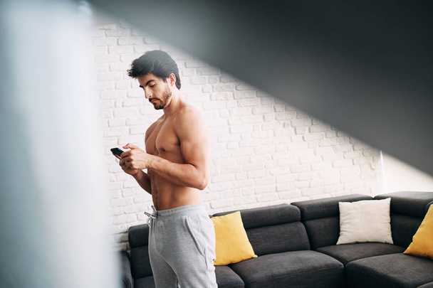 Hombre haciendo ejercicio en casa con aplicación en el teléfono móvil
 - Foto, Imagen