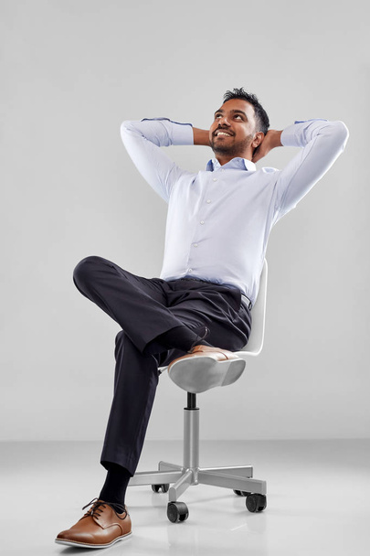 smiling indian businessman sitting on office chair - Fotó, kép