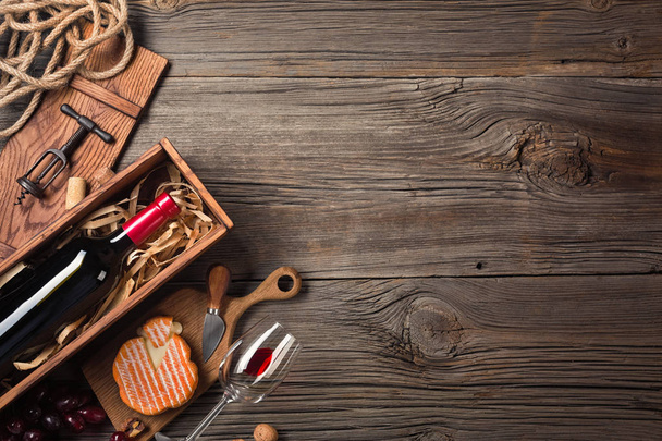 Czerwone wino w polu z szkła, korkociąg i serek na drewnianym stole stary. Widok z góry z miejsca na życzenia - Zdjęcie, obraz