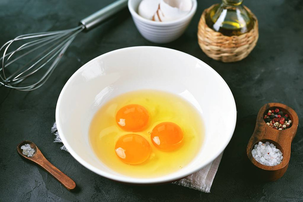 Three raw eggs in a bowl for cooking scrambled eggs. - Фото, изображение