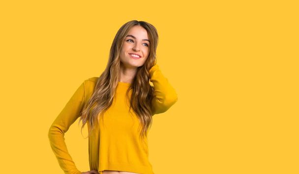 mladá dívka s žlutý svetr přemýšlel myšlenka při poškrábání hlavu na izolované žluté pozadí - Fotografie, Obrázek