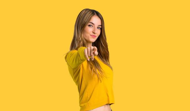 молодая девушка с желтым свитером указывает пальцем на вас с уверенным выражением на изолированном желтом фоне
 - Фото, изображение