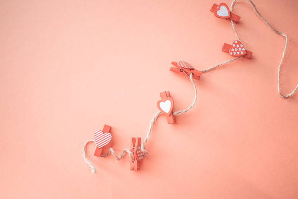 Valentines Day concept. Small clothespins with hearts on a coral background. field for text. - Фото, изображение