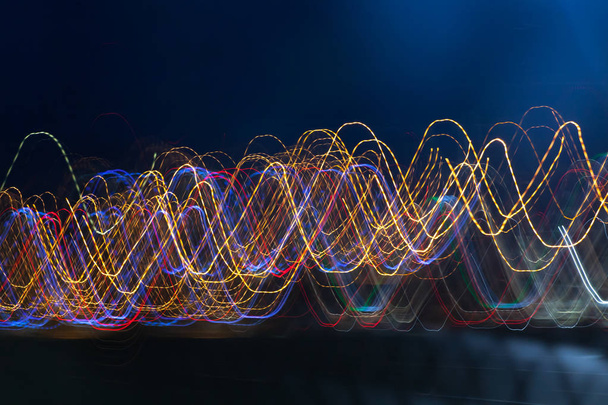 Abstract blurred colorful light effect on a black background. Long exposure photo of moving camera. - Photo, Image