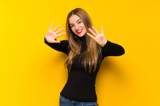 Nuori kaunis nainen yli keltainen tausta laskenta yhdeksän sormilla
 - Valokuva, kuva