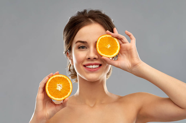smiling woman with oranges over grey background - Фото, изображение