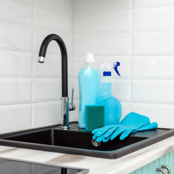 A set of blue cleaning products and tools for cleaning the kitchen is near the kitchen sink. - Photo, Image