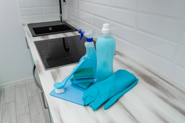 A set of blue cleaning products and tools for cleaning is on the kitchen table. - Zdjęcie, obraz