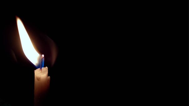 Ένα μικρό κόκκινο κερί αναμμένο πάνω σε μαύρο φόντο - Φωτογραφία, εικόνα