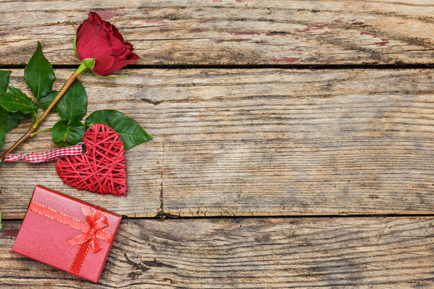 Ημέρα του Αγίου Βαλεντίνου έννοια. Κόκκινο τριαντάφυλλο, δώρο πλαίσιο και ψάθινα καρδιά σε μια ρουστίκ ξύλινα μαυροπίνακα με αντίγραφο χώρο για το κείμενο. - Φωτογραφία, εικόνα