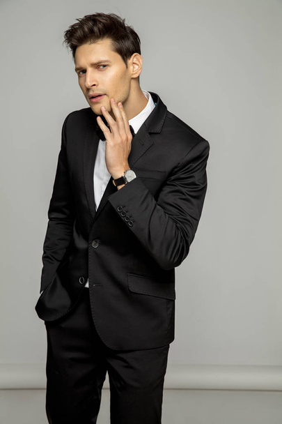 Handsome man in black suit over gray background - Fotoğraf, Görsel