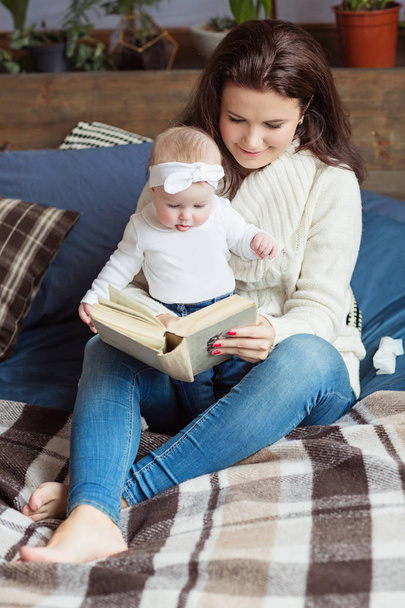 Mother and little daughter are playing, reading a book, lying and relax in the bed. Happy family concept - Foto, Bild