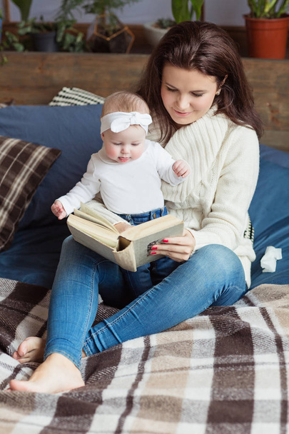 Mother and little daughter are playing, reading a book, lying and relax in the bed. Happy family concept - Foto, Bild