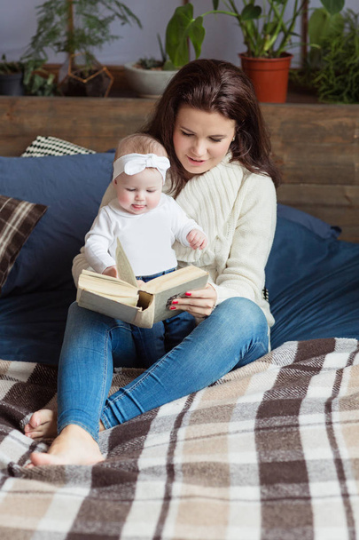 Mother and little daughter are playing, reading a book, lying and relax in the bed. Happy family concept - Foto, Imagen