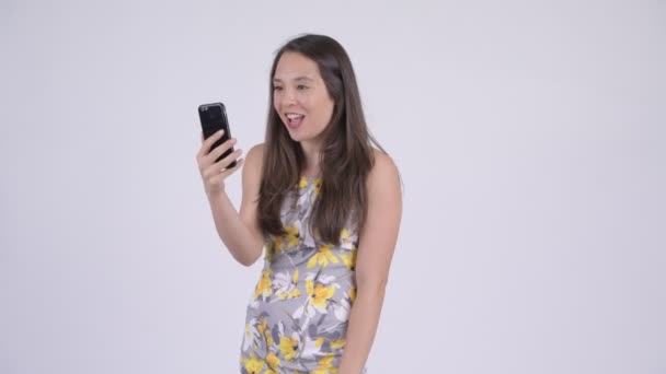 Young happy multi-ethnic tourist woman video calling and showing phone - Кадри, відео
