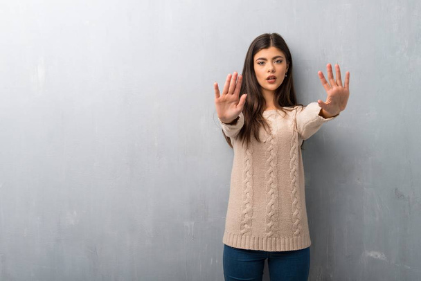 Nastolatek dziewczyna sweter na ściana, co czyni gest stop dla rozczarowany opinię - Zdjęcie, obraz