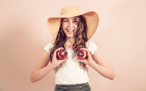 Portrait of a girl in a summer hat with fruit in her hands, concept of style and summer days - Photo, Image