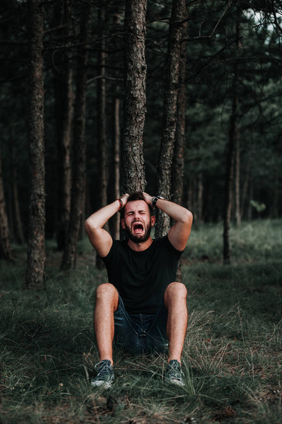 Κατάθλιψη νεαρός κάθεται μόνος στο δάσος - Φωτογραφία, εικόνα