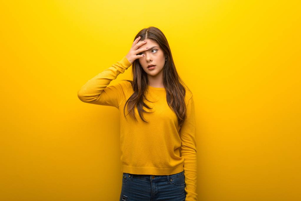 Teenager girl on vibrant yellow background with surprise and shocked facial expression - Photo, Image