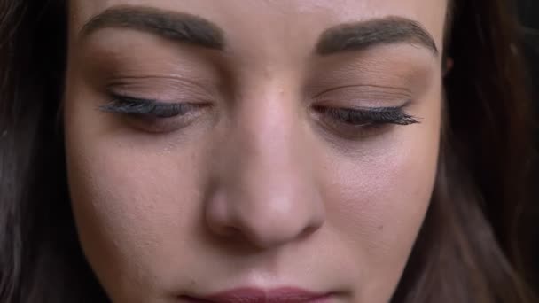 Nahaufnahme-Augenporträt der jungen langhaarigen brünetten Kaukasierin, die lächelnd in die Kamera auf schwarzem Hintergrund schaut. - Filmmaterial, Video