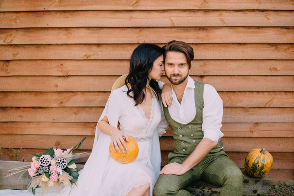 couple dressed in style boho sit and hugging at wall of house - Photo, image