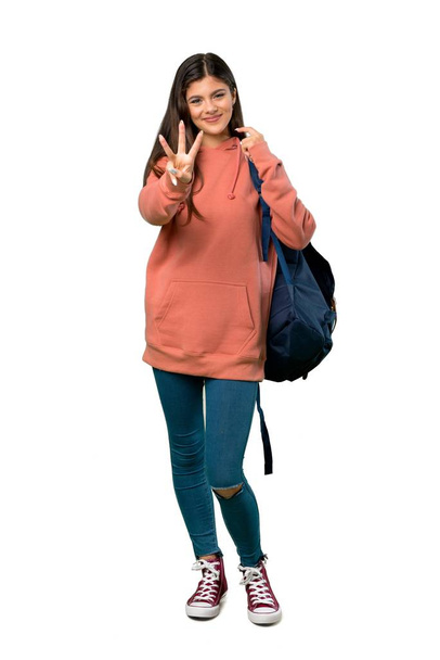 A full-length shot of a Teenager girl with sweatshirt and backpack happy and counting three with fingers - Photo, Image