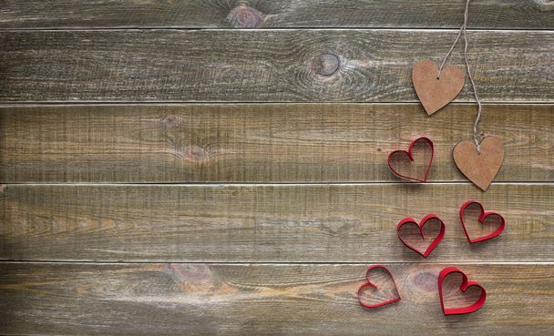 Valentines. 14 February concept. Two wooden hearts tied with string and a lot of red hearts on brown vintage wooden background. Space for text. - Photo, Image