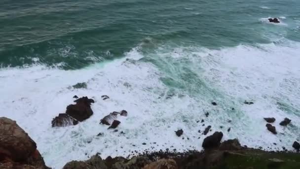 Meriaallot törmäävät kiviin. Merimaisema, jossa on sinisiä aaltoja, valkoista vaahtoa ja kiviä. Näkymä horisonttiin jyrkänteeltä. Pilvinen sää
 - Materiaali, video