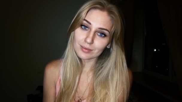belle jeune femme blonde aux yeux bleu vif sur un fond sombre flirte avec la caméra, flirtant et souriant
 - Séquence, vidéo