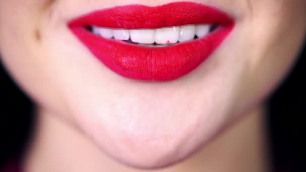 Verleidelijke lichte glimlach van het meisje close-up, rode lippenstift op de lippen, Sneeuwwitje zelfs tanden besmeurd met rode lippenstift, een vrouw glimlacht, bijt speels op haar lip - Video