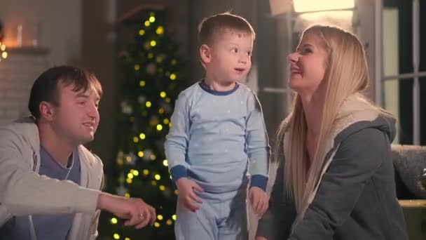 Happy parents with their son playing sitting on the bed in pajamas at Christmas A pillow fight at Christmas before the new year - Footage, Video