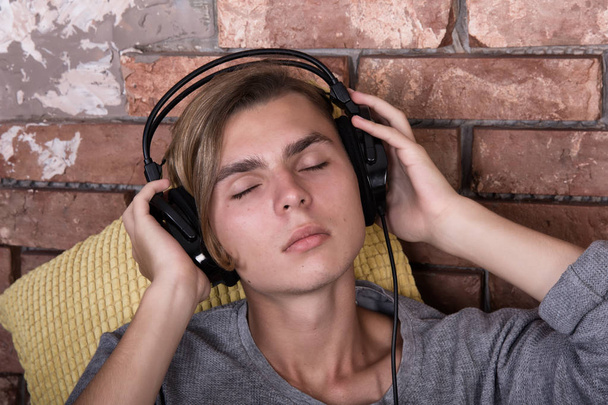 Een student luistert naar muziek. Ontspannen na de Universiteit.  - Foto, afbeelding