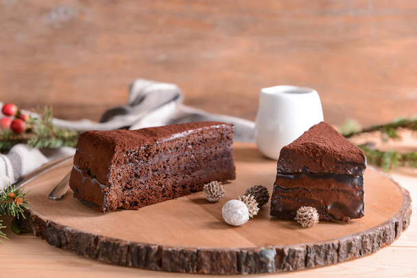 Дерев'яна дошка з шматочками смачного шоколадного торта на столі
 - Фото, зображення