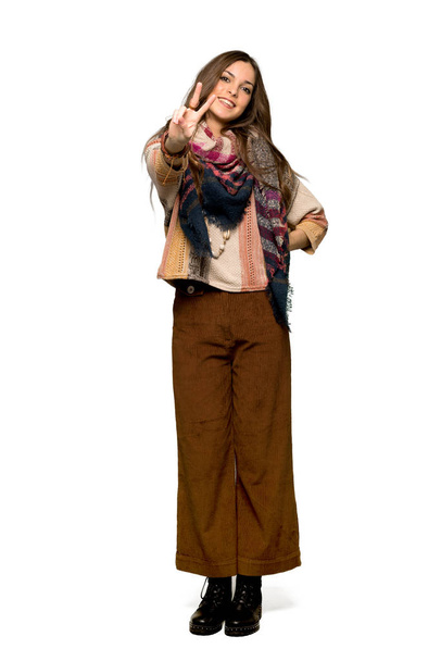 Tiro completo de Jovem hippie mulher sorrindo e mostrando sinal de vitória no fundo branco isolado
 - Foto, Imagem