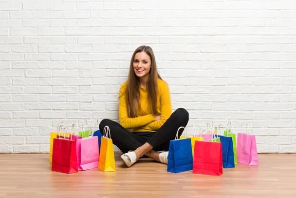 Fiatal lány sok bevásárló táskák, megtartva a karokat, miközben mosolyogva keresztbe - Fotó, kép