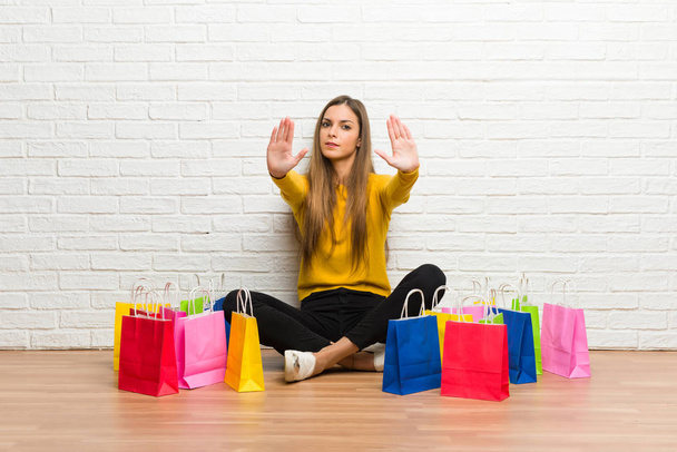 Девушка с большим количеством сумок для покупок делает стоп-жест ради разочарования в мнении
 - Фото, изображение
