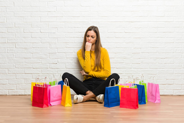 Mladá dívka s množstvím nákupních tašek pochybnosti - Fotografie, Obrázek