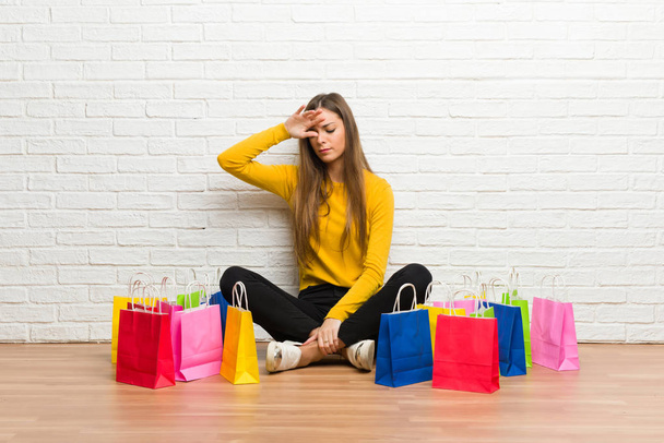 Young girl with lot of shopping bags with tired and sick expression - Photo, Image