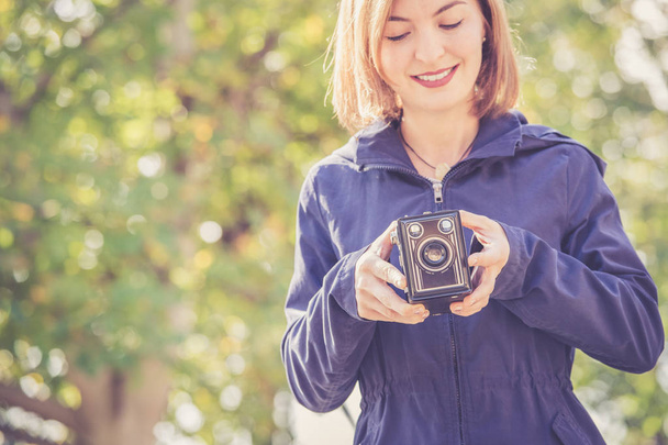 Cute girl is making pictures with a vintage camera, outside - Foto, immagini